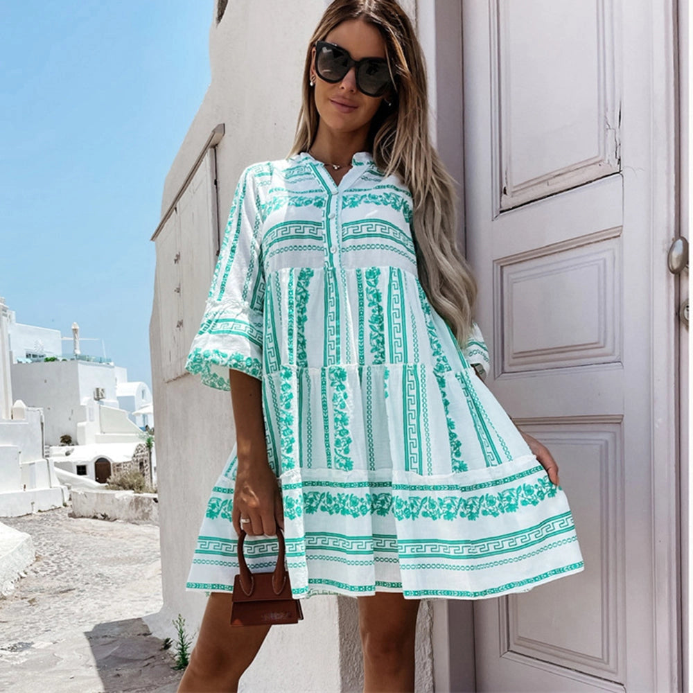 A woman wearing a green and white geometric flowy summer dress with a collar in a casual Mediterranean style, accessorized with sunglasses.