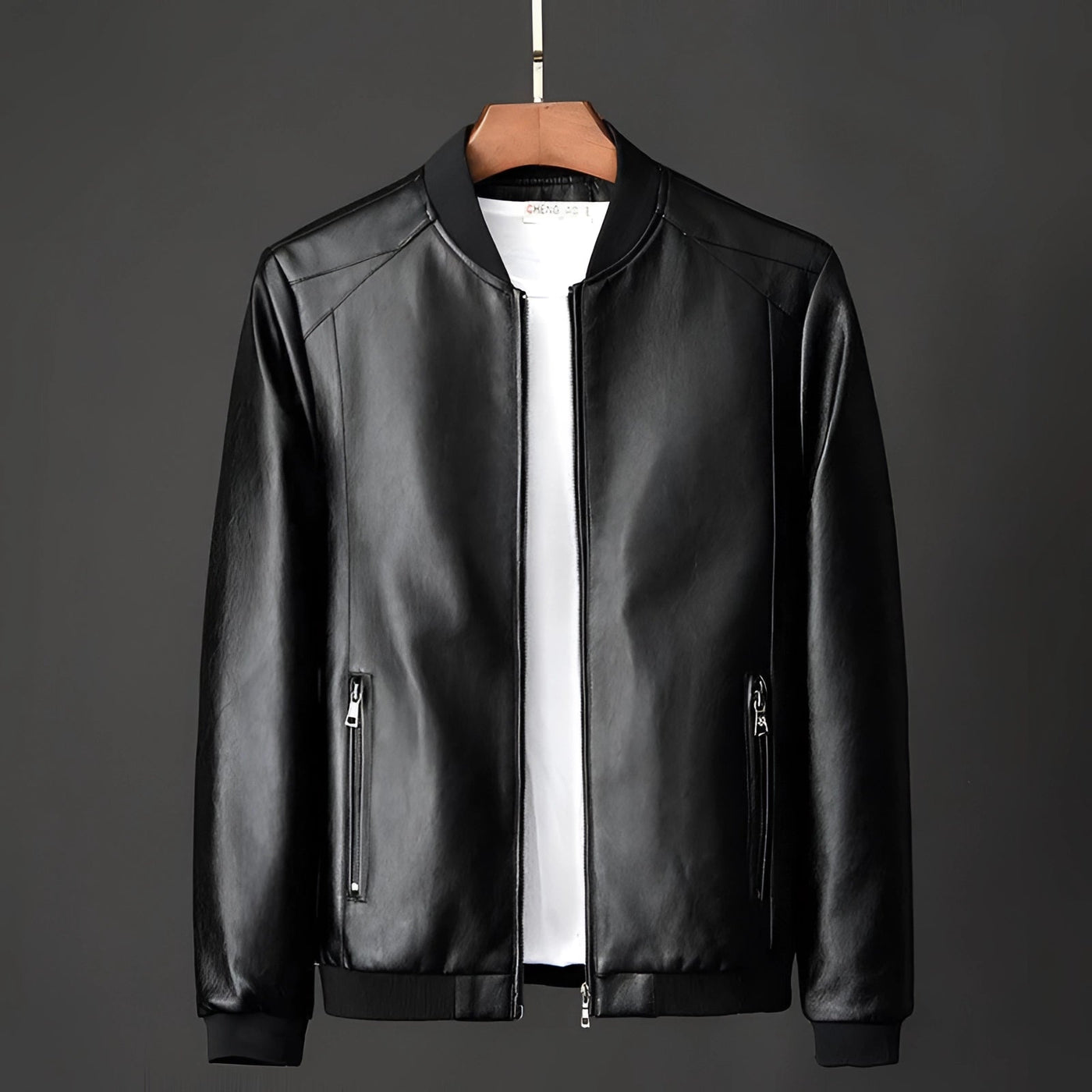 Men's Premium Black Leather Bomber Jacket with minimalist design on clothes hanger showing collar, sleeves, and dress shirt underneath.