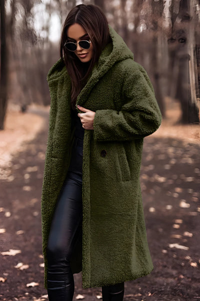 Woman wearing oversized gray faux fur winter coat, black sunglasses, and black pants.