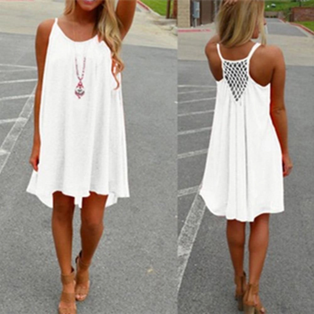 Woman wearing a white sleeveless high-low summer dress with a flowy crochet back, smiling and posing to showcase the dress's elegant design and fit.